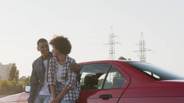 istock Happy man and woman embracing while leaning at car outdoors. Slow motion 2135146215