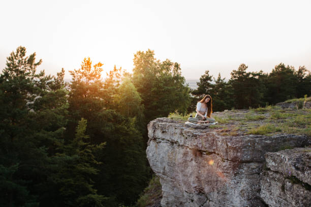 A young beautiful woman performs a Chinese tea ceremony in the mountains at sunset.