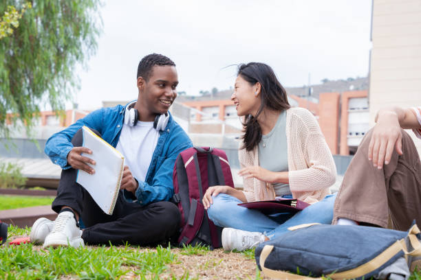 istock Two multiracial college students sitting together on campus lawn reviewing exam 2135149406