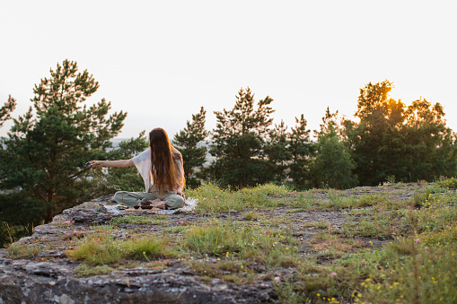 A young beautiful woman performs a Chinese tea ceremony in the mountains at sunset.