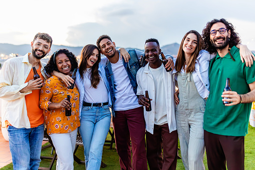 Group portrait of young diverse friends standing together at rooftop party. Friendship and youth community concept.