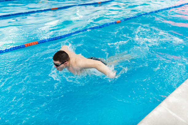 istock Young man swims in an indoor pool 2135229786