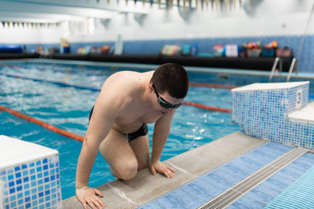 istock Young man emerges from the water in an indoor pool 2135230318