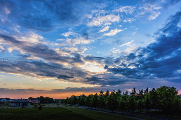 spring evening sky sunset with various clouds over trees and buildings