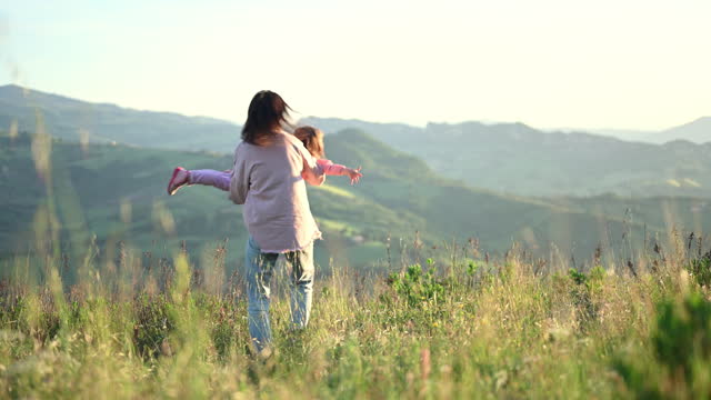 Mother with daughter playing outdoors in mountains.