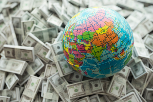 Globe on US dollar bill banknotes pile background. World business, economy, global financial and commercial trading concept.
