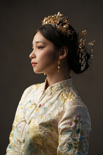 Close up of a beautiful Asian Chinese woman in traditional white bridal tea dress and headwear looking away from camera