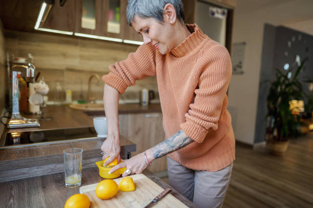 istock Mature woman with tattooed forearm in the kitchen making lemonade 2135284477