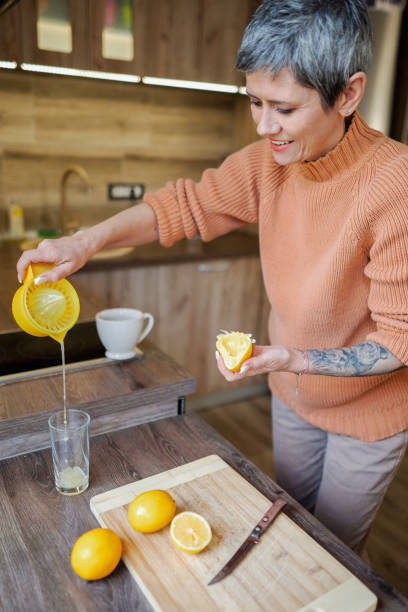 istock Mature woman with tattooed forearm in the kitchen making lemonade 2135286045