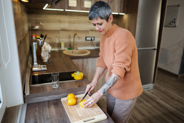 istock Mature woman with tattooed forearm in the kitchen making lemonade 2135288201