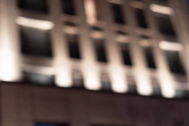 Blurred office building with illuminated facade exterior at night. Blurry modern business building  with bokeh light and defocused dots. Blur windows office building