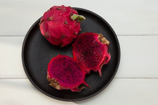 A Dragon fruit on black plate with white background