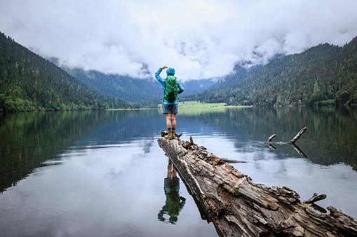 Hiking woman walking on a one plank bridge in high altitude mountains