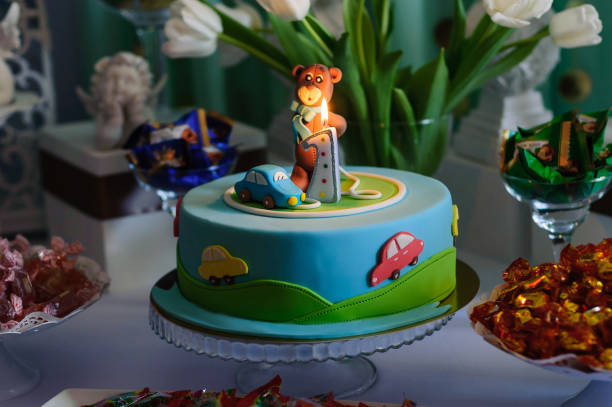 クマ、車、ろうそくで飾られた青いバースデーケーキ
