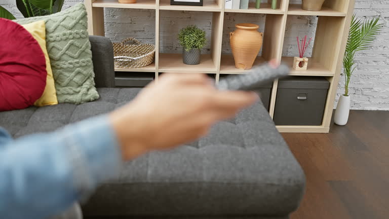 Man holding remote in cozy modern living room.