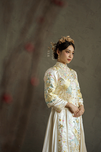 Beautiful Asian Chinese woman in traditional white bridal tea dress and headwear looking away from camera