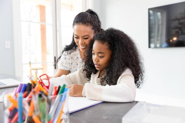 istock Mom takes break from work to help daughter with assignment 2135382682