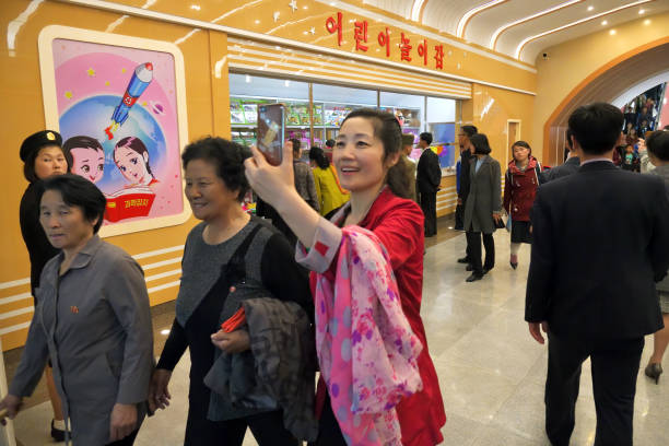 Pyongyang, North Korea - May 1, 2019: People at the Kaeson subway station in Pyongyang Metro. Local woman takes a picture on smartphone