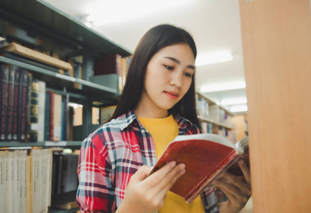 istock Students are reading and looking for books to study, make reports, find useful information on the bookshelves in the library. Concept of reading, learning and intelligence. 2135415496