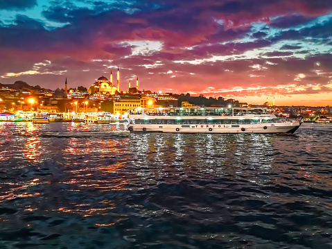 Istanbul, Turkey - October 28, 2019: A tourist ship Turyol sails in the reflected lights of night Istanbul, Turkey. Evening cityscape of the Golden Horn Bay and the promenade of a Turkish city