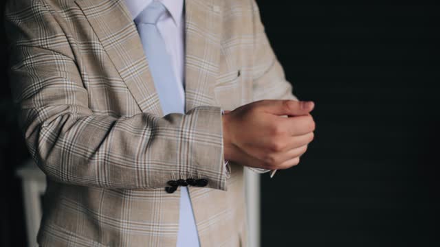 A man adjusts his jacket while getting dressed for a meeting. Filming of meeting fees
