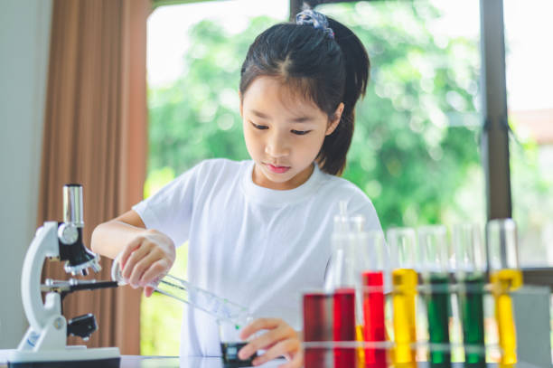 istock little scientist looking through a microscope and test tubes filled with chemicals for learning about science and experiments. 2135451682