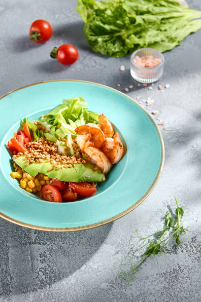 istock Avocado salad bowl with smoked salmon and fresh vegetables on a sunlit textured surface 2135455278