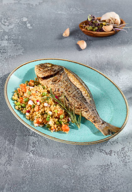 istock Grilled Dorado with Bulgur and Vegetable Medley Elegantly Served on a Turquoise Plate 2135455826