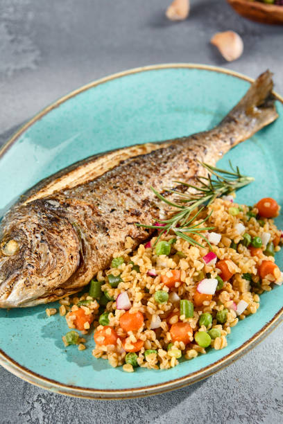 istock Grilled Dorado with Bulgur and Vegetable Medley Elegantly Served on a Turquoise Plate 2135455831