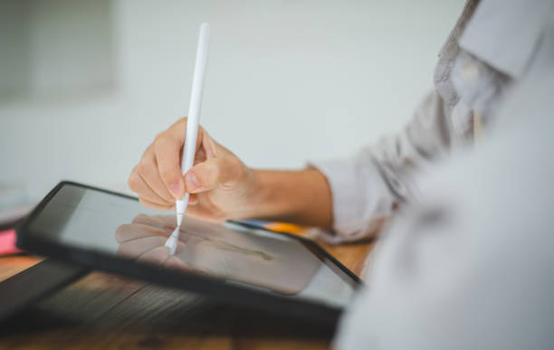 istock close up hand holding a pen, drawing on the tablet. Communicating and researching online. 2135456931