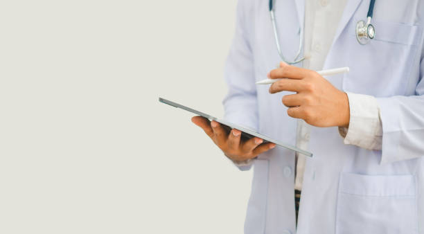 istock Portrait doctor with a stethoscope and using digital tablet stands confidently ready for healthcare visitor in hospital or clinic. 2135463818