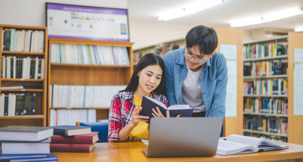 istock Students are consulting each other working on laptops and searching for books to study, make reports, find useful information in university room. Concept of reading, learning and intelligence. 2135470370