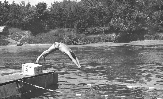 Retro photo of a young man jumping into the river. THE USSR. 70s of the 20th century.