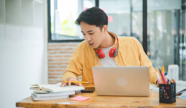 istock Young Asian college student working and learning on laptop In the cafe. Searching for knowledge online. 2135476751