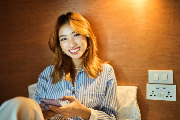 istock Smiling young woman checking her phone in her hostel dorm bed 2135478399