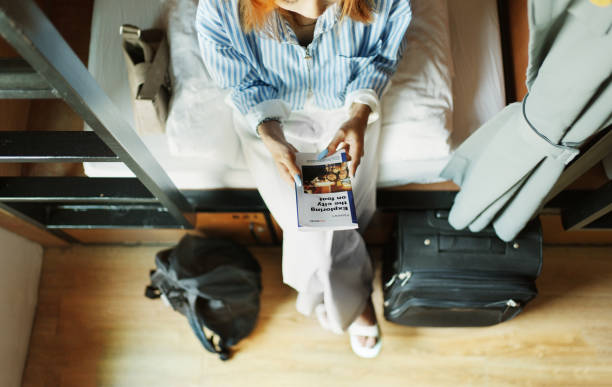 Young woman sitting in a hostel dorm and reading a travel guide