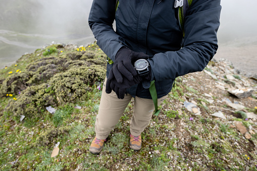 Successful woman hiker  set the sports watch at mountain top in tibet