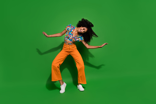 Full body photo of young lady wear trendy vintage garment shaking head chevelure hair doing a waves isolated on green color background.