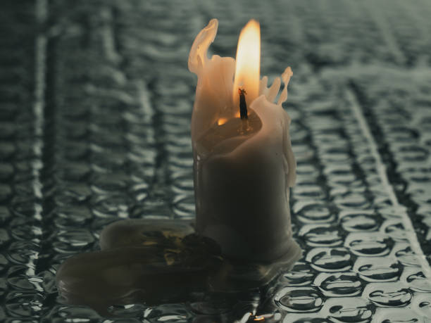 A white candle on ground with water droplets