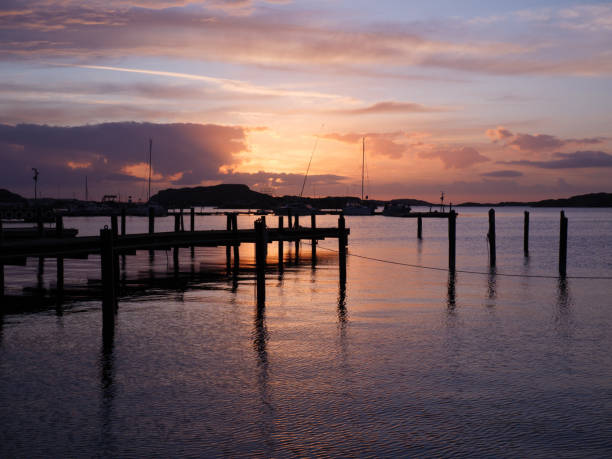 istock Sunset over a dock on water with dark clouds, tranquil scene 2135507137