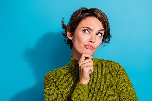 Photo of minded confused girl wear khaki clothes arm touch chin look up empty space hmm dilemma doubt isolated on cyan color background.