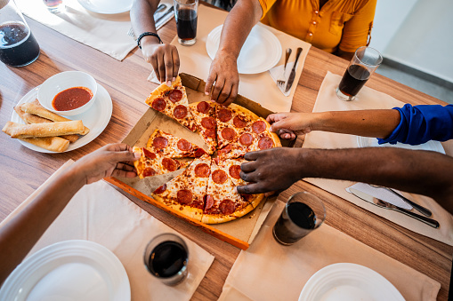 Close-up of family sharing and picking slice of pizza at home