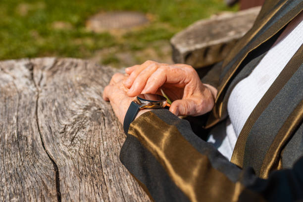 elderly woman with smart watch fitness band checking her pulse,outdoors on the old wooden table,sumer sunny day. closeup. - 11874 - fotografias e filmes do acervo