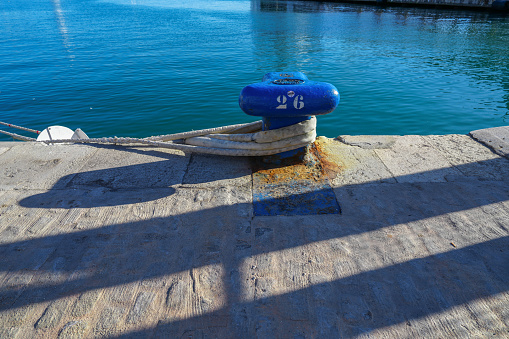 Close up of big blue mooring cleat and rope on the pier in Malaga Spain