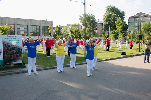 Dnepr, Ukraine - 06.21.2021: A group of elderly people doing health and fitness gymnastics with a ball in the park.