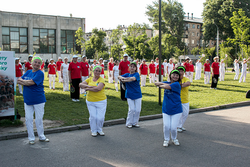 Dnepr, Ukraine - 06.21.2021: A group of elderly people doing health and fitness gymnastics with a ball in the park.