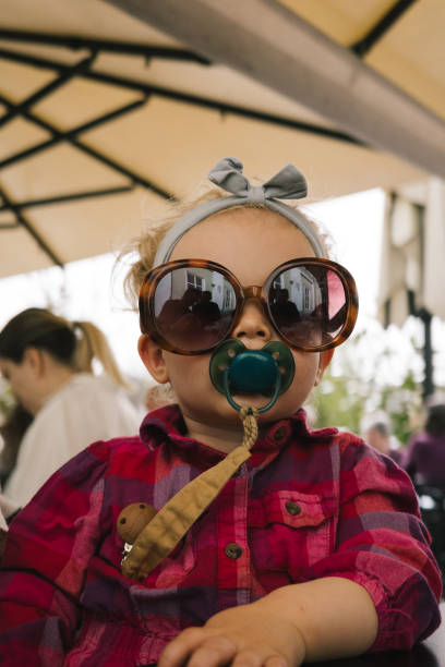 Toddler relaxes in outdoor cafe and plays with sunglasses