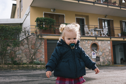 Toddler with pacifier walks outdoors in winter