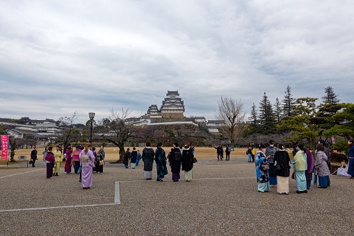 Famous Unesco Word Heritage site Himeji-jo castle with Japanese women in traditional kimono clothing on a cloudy gray winter day. Photo taken February 1st, 2024, Himeji, Japan.