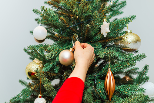 Young girl decorating the Christmas tree at home,holding Christmas bauble in her hand. holiday concept